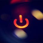 Why IT Asks You to Restart Your Computer | GC Network Solutions Lit red power button icon on a dark blurred background, indicating power on/off functionality.
